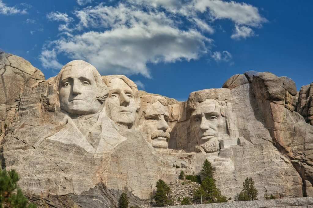 faces curved on a rocky mountain side under a blue sky